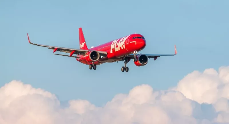 Avin de pasajeros de la aerolnea islandesa PLAY en vuelo con nubes de fondo.