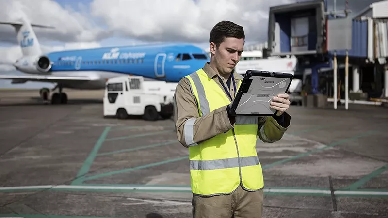 Operario con un dispositivo Toughbook de Panasonic en una pista aeroportuaria.